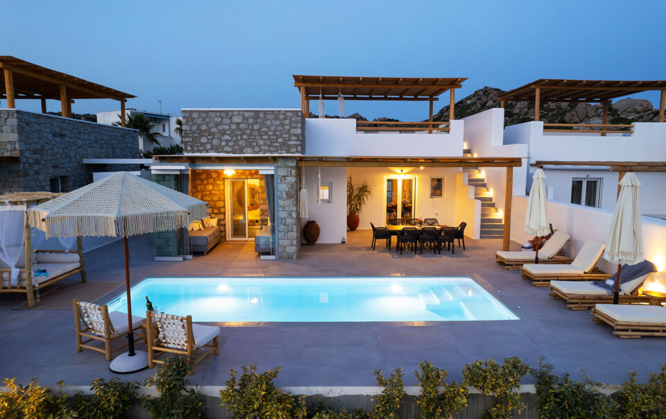 Exterior view of the villa at dusk, with lights illuminating the surroundings as the sun sets. Olives Seaside Villas, Plaka, Naxos
