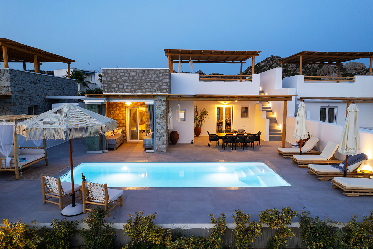 Exterior view of the villa at dusk, with lights illuminating the surroundings as the sun sets. Olives Seaside Villas, Plaka, Naxos